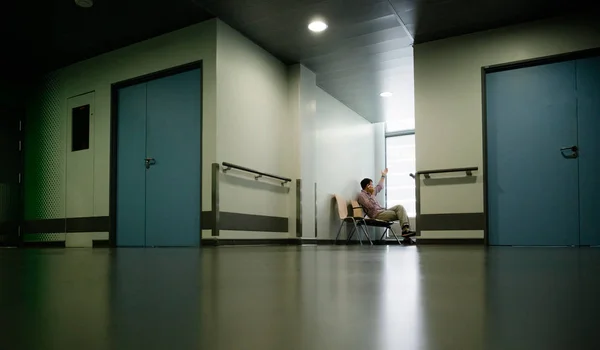 Man using smartphone in hospital waiting room