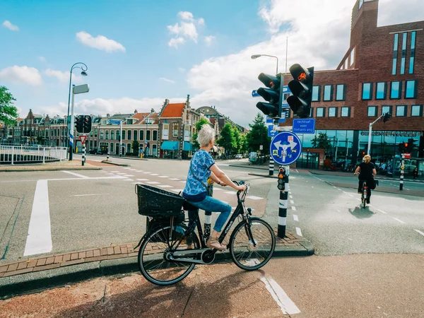Елегантна Голландська жінка їзда на велосипеді зелене світло — стокове фото