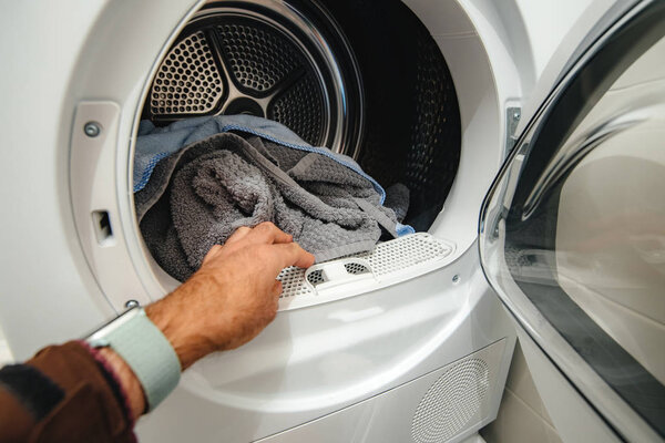 Man hand arranging clothes in the modern household machine