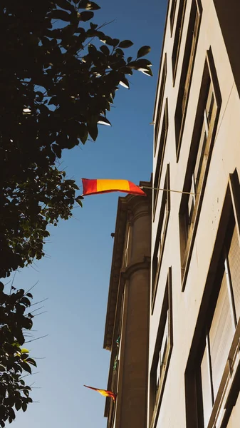 Angle bas de grand bâtiment avec drapeau espagnol agitant — Photo