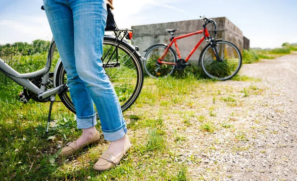 Ноги взрослой женщины возле велосипеда — стоковое фото