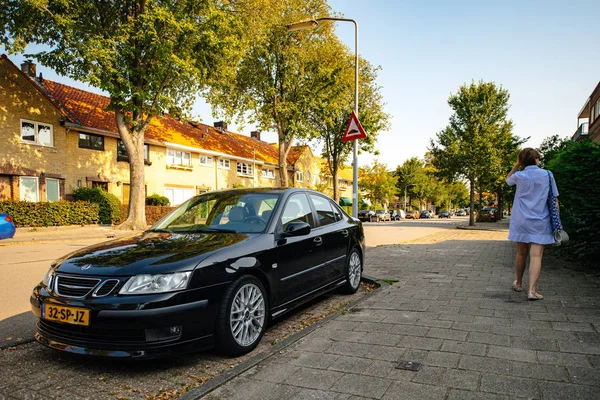 Женщина, идущая рядом с черной роскошью Saab Limouse — стоковое фото