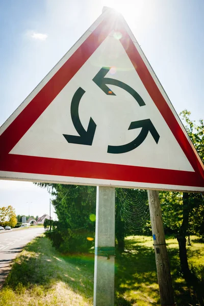 Yeni Roundabout işareti güneş ışığı parlaması Closeup — Stok fotoğraf