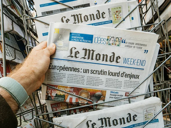 POV man hand holding reading latest Le mondenewspaper — Stock Photo, Image