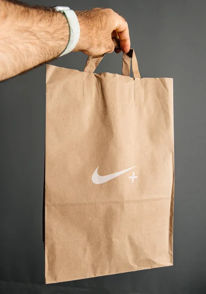 Homem mão segurando novo saco de papel Nike Plus — Fotografia de Stock