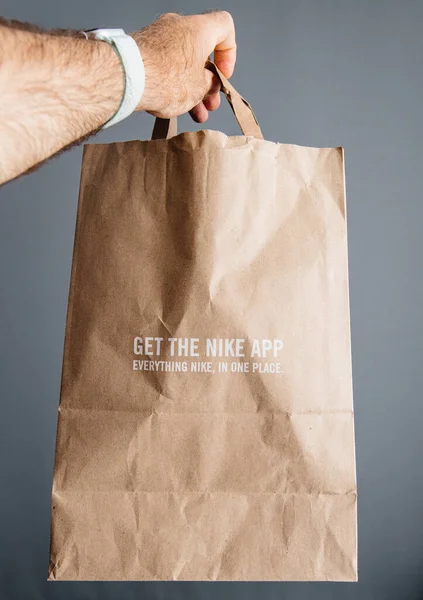 Mano del hombre sosteniendo nueva bolsa de papel Nike Plus —  Fotos de Stock