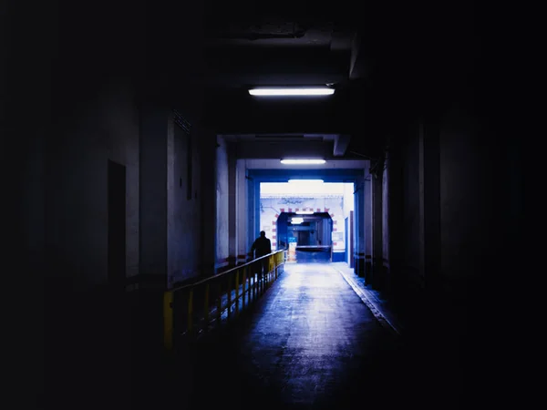 Silueta de hombre caminando a través de un túnel oscuro — Foto de Stock