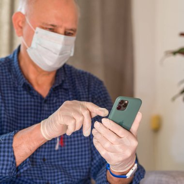 Maskeli ve eldivenli Coronavirus sırasında Apple iPhone 11 Pro akıllı telefon kullanılıyor