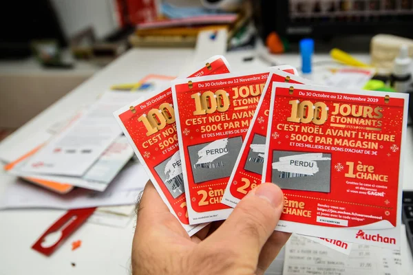 Segurando cupons de loteria riscados bilhetes de Supermercados Auchan com Perdu Lost sinal — Fotografia de Stock