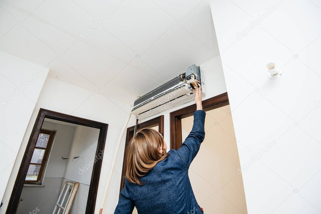 Woman trying to repair newly installed air conditioner wall ac unit