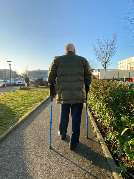 Hombre mayor caminando bastones en el estacionamiento del hospital grande — Foto de Stock