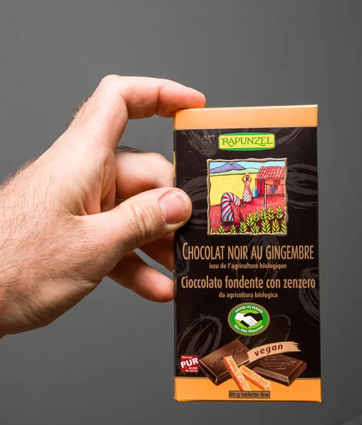 Handen håller mot grå bakgrund paket med mörk choklad — Stockfoto