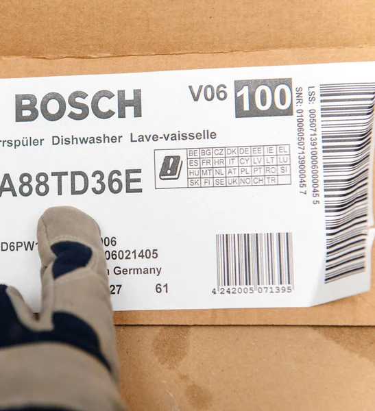 Instalador masculino apuntando a una caja de cartón del lavavajillas Bosch —  Fotos de Stock
