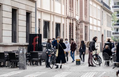 Strasbourg 'un merkezinde koruyucu maskeler takan insanlar buluşuyor.