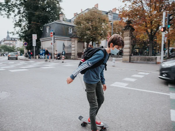 Young boy on skate in central part of the city wearing a protective mask — Stock Photo, Image