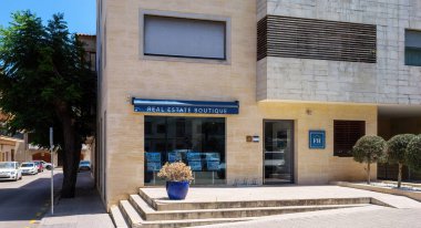 Pollenca, İspanya - 24 Temmuz 2025: Pollenca Mallorca İspanya 'daki sokak manzaralı emlak butiği mavi tenteli ve girişte saksı bitkileri.