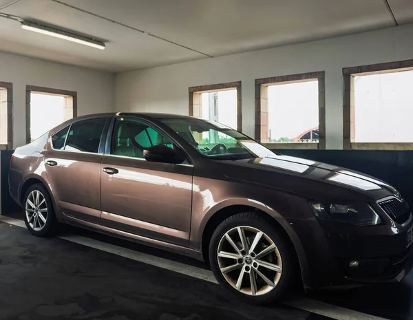 Berlin, Almanya - 28 Haziran 2025: Kahverengi Skoda Octavia Sedan, yan camlardan içeri ışık sızan kapalı bir otoparka park etti.