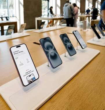 Paris, Fransa - Sep 19, 2025: iPhone 16 Plus akıllı telefonlar bir Apple Store 'daki ahşap bir masada sergilendi, arka planda müşterilerin baktığı tasarım ve özellikleri vurgulanıyor.