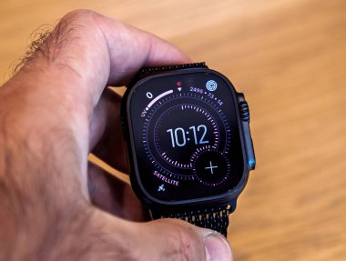 Paris, Fransa - 19 Eylül 2025: Yeni Apple Watch Ultra 'yı elinde tutan, zaman, aktivite takibi ve uydu bilgileri içeren parlak dijital saat yüzünü gösteren bir kişinin yakın çekimi.