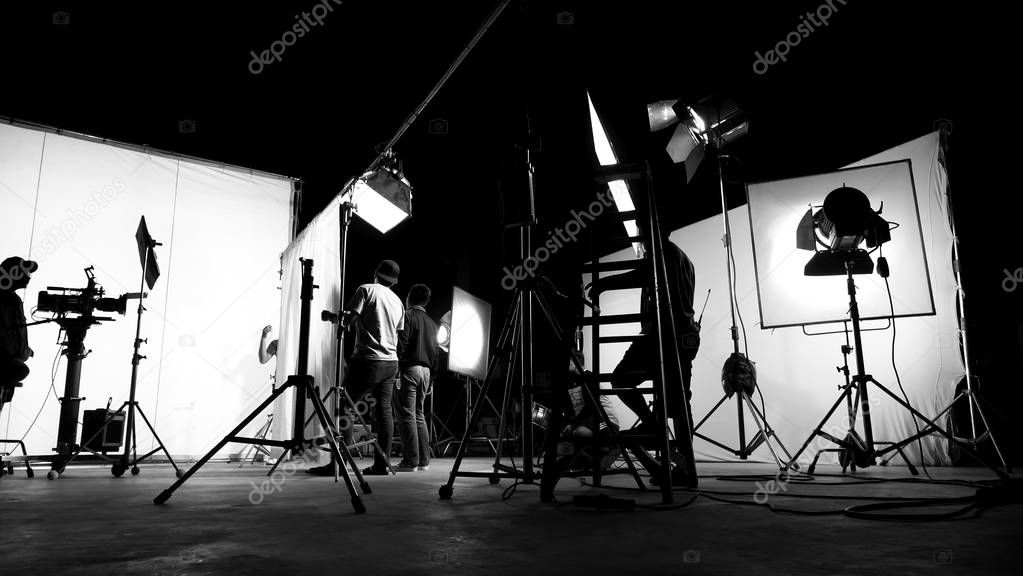 Behind the scenes of TV commercial movie film or video shooting production which crew team and camera man setting up green screen for chroma key technique in big studio.