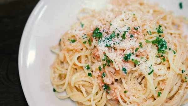 Close-up image of spaghetti sauce tarako which made from fresh cod fish in Japan and mixed with Thai coriander on the top of white plate and very famous italian-japanese menu dish in Thailand restaurant.