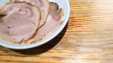 Chashu domuz eti 3 adet dilim beyaz renk çanak ve ahşap masa Tepesi tonkotsu ramen Sapporo Hokkaido Japonya'deki ünlü geleneksel gıda için hangi ek menü.