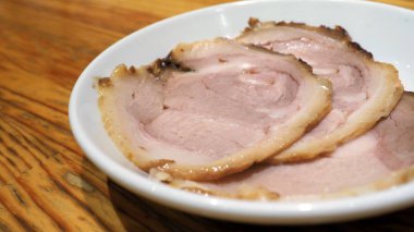 Chashu domuz eti 3 adet dilim beyaz renk çanak ve ahşap masa Tepesi tonkotsu ramen Sapporo Hokkaido Japonya'deki ünlü geleneksel gıda için hangi ek menü.