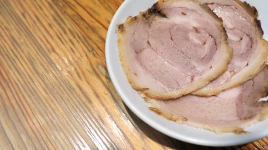 Chashu domuz eti 3 adet dilim beyaz renk çanak ve ahşap masa Tepesi tonkotsu ramen Sapporo Hokkaido Japonya'deki ünlü geleneksel gıda için hangi ek menü.
