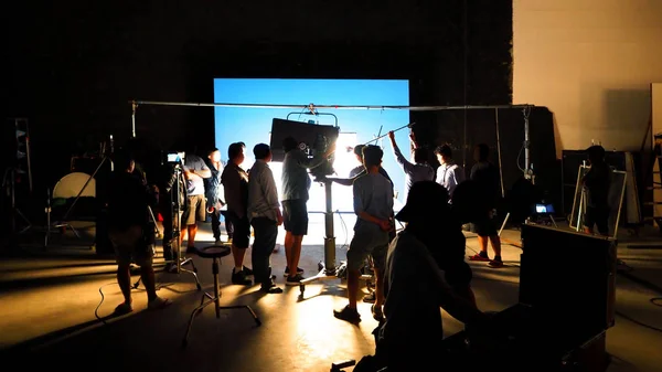 幕后的视频制作拍摄工作室的剪影 有专业的设备 如相机 三脚架和蓝屏背景设置的色度关键技术在后处理和许多电影船员团队工作的电视广告或 — 图库照片