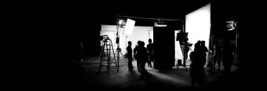 Silhouette images of video production behind the scenes or b-roll or making of TV commercial movie that film crew team lightman and cameraman working together with director in big studio with professional equipments  clipart