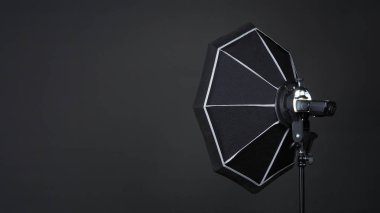 Profesyonel fotoğraf stüdyosunun yumuşak kutusu ve tripodunda siyah arka planda çekim yapmadan önce ışığı daha yumuşak, daha sert ya da daha keskin ekipler için şekillendirmeye hazır üç ayaklı fotoğraf ya da video prodüksiyonu için ışık var..