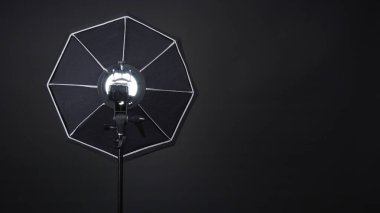 Profesyonel fotoğraf stüdyosunun yumuşak kutusu ve tripodunda siyah arka planda çekim yapmadan önce ışığı daha yumuşak, daha sert ya da daha keskin ekipler için şekillendirmeye hazır üç ayaklı fotoğraf ya da video prodüksiyonu için ışık var..