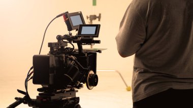 Yüksek çözünürlüklü kamera, monitörler ve ekipmanlı LED ışığı gibi profesyonel ekipmanlarla büyük stüdyo prodüksiyonunda çevrimiçi ticari veya web film kaydı yapan kamera arkasında