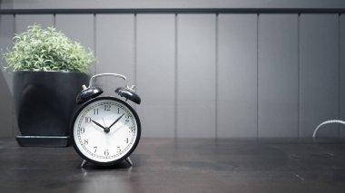 Çalışan ahşap masada siyah renkli klasik çalar saat 