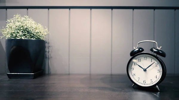 Relógio de alarme clássico de cor preta na mesa de madeira de trabalho — Fotografia de Stock