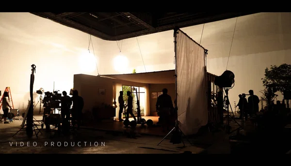 Detrás del set de producción e iluminación de video de rodaje para filmar qué equipo de filmación trabaja y silueta sombra de cámara y equipo profesional en gran estudio para publicidad comercial . — Foto de Stock