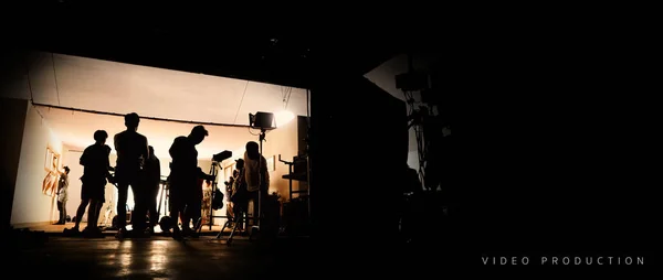 Bakom inspelningen videoproduktion och belysning som för filmning som film Crew team arbetar och siluett Shadow of Camera och professionell utrustning i Big Studio för kommersiell reklam. — Stockfoto