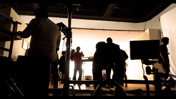 Detrás del set de producción e iluminación de video de rodaje para filmar qué equipo de filmación trabaja y silueta sombra de cámara y equipo profesional en gran estudio para publicidad comercial . —  Fotos de Stock