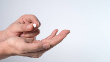 İnsanların pandemik virüsten korunmalarını ve sağlıksız ve hastalıktan kurtulmalarını sağlayan bir ilaç hapını ellerinde tuttukları ya da aldıkları yakın çekim görüntüleri. Stüdyo çekimi ve temiz arkaplan.