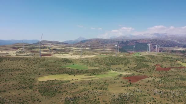 Windkraftanlagen mit einem Traktor auf dem Feld. Traktor bearbeitet staubige Felder in der Nähe der Basis von Windkraftanlagen in Thrakien, Türkei — Stockvideo