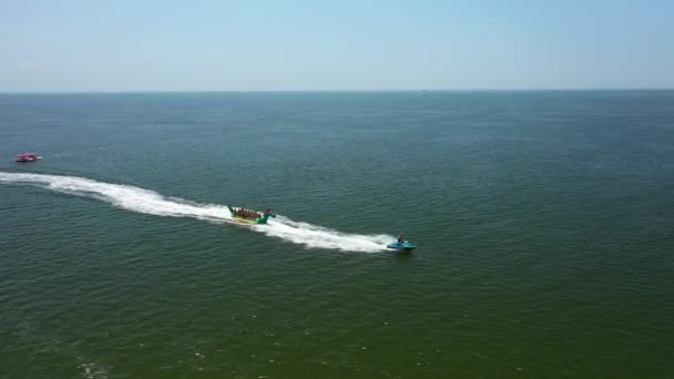 Vlucht Drone Luchtmacht drone na Banana boot vol met mensen die plezier hebben in zee — Stockvideo