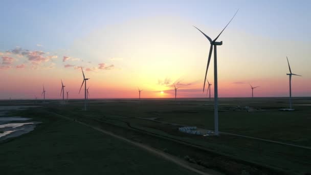 Farma wiatrowa na tle pięknego, złotego zachodu słońca. Produkcja energii odnawialnej dla ekologicznego świata. Widok z lotu ptaka. — Wideo stockowe