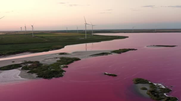 En vindpark mot bakgrund av en vacker kväll gyllene solnedgång. Produktion av förnybar energi för en grön ekologisk värld. Flygbild. — Stockvideo