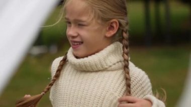 Beyaz bir kazak içinde pigtails olan küçük bir kızın portresi. Çocukluk hafızası. Yavaş hareket Vintage Times. Aile sınırları. Aile portresi. Aile Chronicle