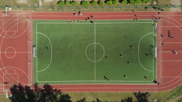 Jogo de futebol aéreo. Duas equipas a jogar futebol ao ar livre, vista de cima. Jogo de futebol ao ar livre, campo verde com marcações, jogadores correndo ao redor com uma bola — Vídeo de Stock