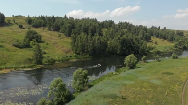 Vue aérienne. Un petit bateau de pêche en caoutchouc avec un moteur se déplace rapidement sur une petite rivière . — Video