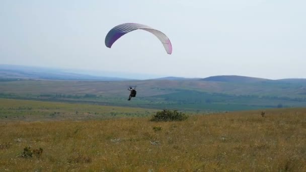 Parapendio estremo che vola contro un cielo blu chiaro, raggio di sole splende nella fotocamera. Parapendio volo esperienza paracadutismo estate . — Video Stock