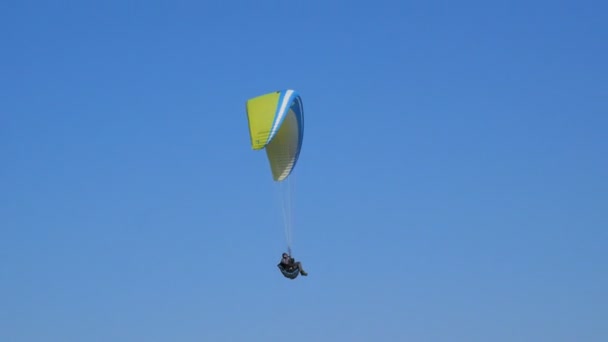 Parapente extremo voando contra um céu azul claro, raio de sol brilha na câmera. Paraglide voo experiência skydive verão . — Vídeo de Stock