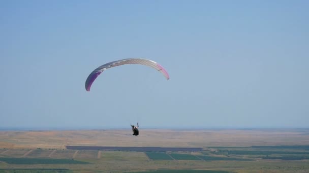 Extreme paraglider flying against a clear blue sky, sunbeam shines into camera. Paraglide flight experience skydive summer. — Stock Video