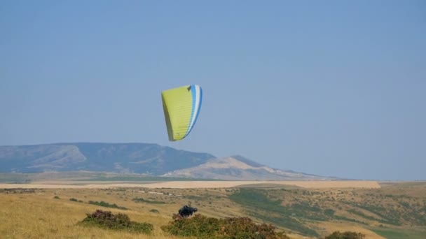 Parapente extremo volando contra un cielo azul claro, el rayo de sol brilla en la cámara. Parapente vuelo experiencia paracaidismo verano . — Vídeo de stock